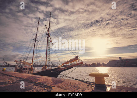 Alte Schoner in einem Hafen bei Sonnenaufgang festgemacht, Farbe getonte Bild. Stockfoto