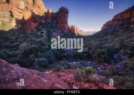 Atemberaubende Aussicht auf Fay Canyon von oben die Baumkronen mit Patches von Schnee auf dem Boden und majestätischen Blick auf Bell Rock und den Courthouse Butte in der Dis Stockfoto