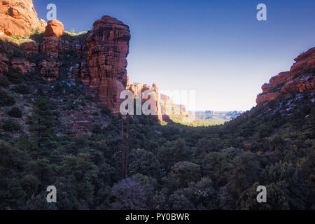 Atemberaubende Aussicht auf Fay Canyon von oben die Baumkronen mit Patches von Schnee auf dem Boden und majestätischen Blick auf Bell Rock und den Courthouse Butte in der Dis Stockfoto