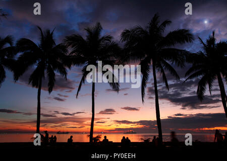 Silhouetten von Menschen und Palmen gegen Himmel und Meer bei Sonnenuntergang, Manila, Philippinen Stockfoto