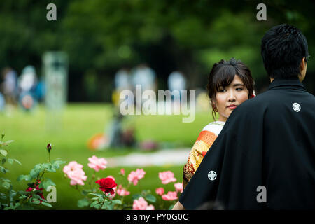 Junges Paar in traditioneller Kleidung im Garten vor der Blumen Posing, Tokyo, Tokio, Japan Stockfoto