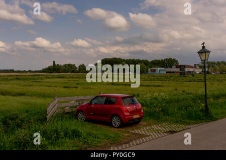 Zaanse Schans - 20. Mai: Rote Suzuki Swift Auto geparkt auf einer Wiese. Zaanse Schans ist ein Unesco Weltkulturerbe Stockfoto