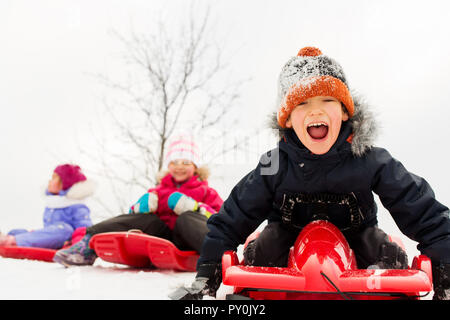 Happy Kids rutschen auf Schlitten im Winter Stockfoto