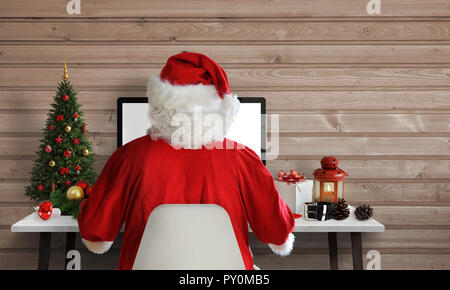 Santa Claus die Arbeit an einem Computer in seinem Büro. Auf Briefe beantworten und Grußkarten per E-Mail. Freier Platz für Text neben. Stockfoto
