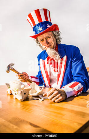 Eine traurige und fast weinen Uncle Sam über einen gebrochenen piggy Bank Holding einen Hammer zu sitzen. Konzeptionelle Schuß für Treasury, Defizite, Bank-, Spar-, Steuer revenu Stockfoto