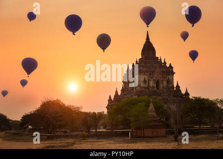 Heißluftballone fliegen über einen Tempel bei Sonnenuntergang, Bagan, Myanmar Stockfoto