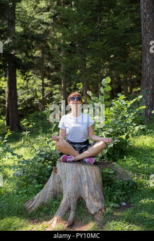 Frau sitzt auf einem Baumstumpf zu meditieren, Bosnien und Herzegowina Stockfoto