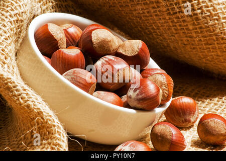 Die Haselnuss in einer weißen Schüssel auf sackleinen Stockfoto