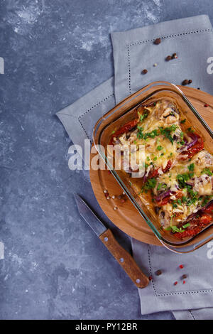 Gebackene Hähnchenschenkel mit Tomaten, Zwiebeln und Käse Chicken Casserole Menü und Restaurant Konzept auf grauem Hintergrund Stockfoto