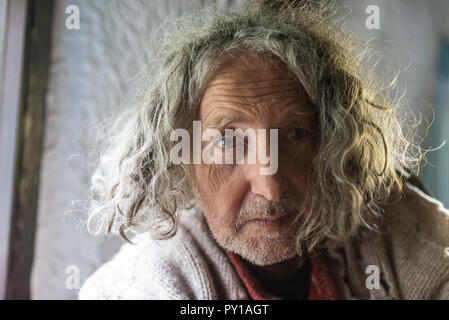 Porträt der alten Mann mit ungepflegten langes graues Haar und Stroh traurig. Stockfoto
