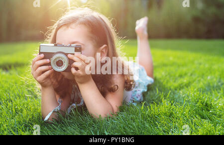 Süße kleine childl liegen auf grünen Rasen und ein Bild aufnehmen Stockfoto