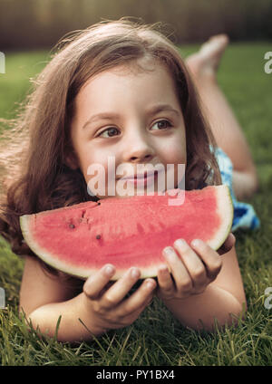 Closeup Portrait von lächelndes Kind holding Wassermelone Schicht im Garten Stockfoto