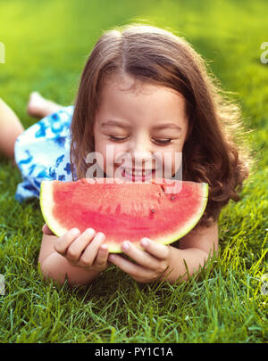 Closeup Portrait von lächelndes Kind holding Wassermelone Schicht im Garten Stockfoto