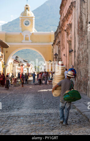 ANTIGUA, GUATEMALA - Februar 24, 2018: unbekannter Mann verkaufen Hüte Spaziergänge unter der berühmten Santa Catalina arch in der touristischen Stadt von Antigua, Guatemala Stockfoto