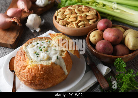 New England Clam Chowder: Ein Brot Schüssel voller Frische, hausgemachte Suppe mit Crackern und Zutaten. Stockfoto