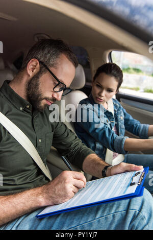 Lehrer schreiben etwas in die Zwischenablage während der Fahrt testen Stockfoto