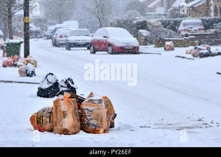 Winter street scene Beutel des Recycling von Abfällen und schwarzen Sack Deponie müll Schnee auf Pflaster für die Abfallwirtschaft Team collection Lkw UK abgedeckt Stockfoto