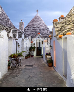 Trulli auf der Straße in Alberobello, Puglia, Italien. Kürbisse haben auf der Traufe platziert wurde Halloween zu feiern. Bei Sonnenaufgang fotografiert. Stockfoto