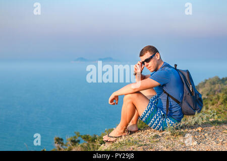 Mann in Sonnenbrille liegt am Rande eines Berges. Stockfoto