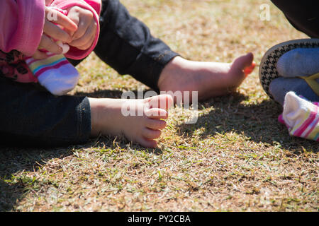 Mutter und Tochter sitzen auf Gras zusammen Stockfoto
