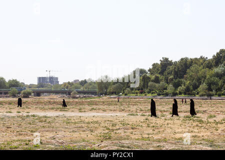 ISFAHAN, IRAN - 20. AUGUST 2016: Frauen in der islamischen Schwarz hijab walking Ion die trockene Zayandeh Fluss, während einer besonders warmen Sommer Bild Stockfoto