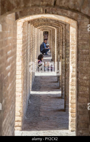 ISFAHAN, IRAN - 20. AUGUST 2016: Perspektive der Antike Steinbögen der Si-o-Seh Pol-Brücke, die mit dem iranischen Volk, Männer und Frauen, sitzen. Es ist Stockfoto