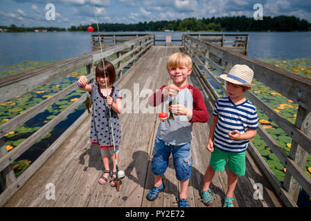 Drei Kinder auf einem Dock mit einem Fang von Fischen stehend, United States Stockfoto