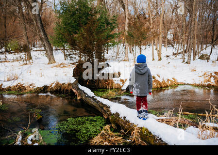 Junge gehen über einen gefallenen Log im Winter, United States Stockfoto