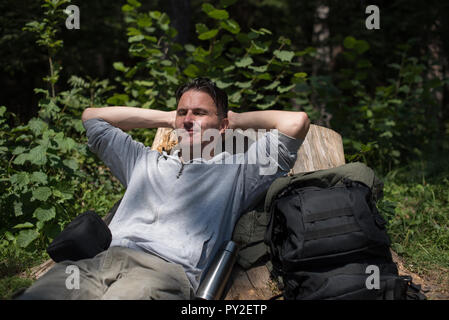 Wanderer lehnte sich gegen einen Baumstumpf im Wald, Bosnien und Herzegowina Stockfoto