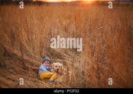 Junge in ein Feld mit seinem Golden Retriever Hund liegend, United States Stockfoto