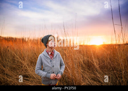 Junge in einem Feld bei Sonnenuntergang stehend, United States Stockfoto