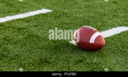 Ein braunes Leder American Football auf einem grünen Kunstrasenplatz Stockfoto