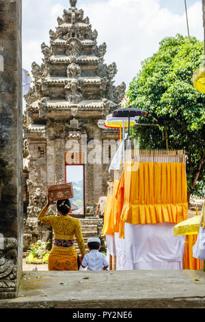 Balinesische Frau in kebaya und Sarong mit keben (Feld für Angebote) und ein Kind im Pura Kehen, balinesischen Hindu Tempel in Bangli Regency, Bali, Indonesien. Stockfoto