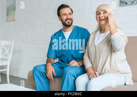 Lächelnde junge Sozialarbeiter im Happy senior Frau sprechen von Smartphone suchen Stockfoto