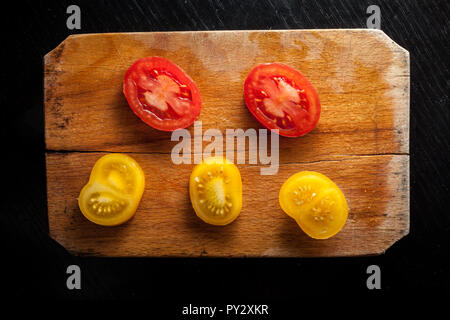 Rote und gelbe Tomaten auf vintage Schneidebrett Stockfoto