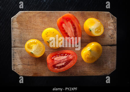 Rote und gelbe Tomaten auf vintage Schneidebrett Stockfoto