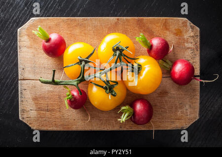 Gelbe Tomaten und Rüben auf vintage Schneidebrett Stockfoto