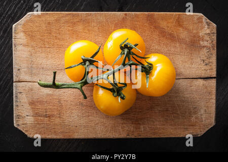 Gelbe Tomaten auf vintage Schneidebrett Stockfoto