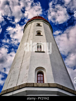 Nahaufnahme von einem weißen Leuchtturm mit 4 Fenstern auf der jeweils anderen. Hintergrund mit blauem Himmel und weißen Wolken. Porträt. Stockfoto