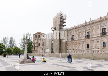 León, Spanien: Pilgern auf dem Camino Frances Route des Jakobswegs sammeln auf dem Bronze Skulptur eines Pilgers auf der Plaza San Marcos. Die fassade Stockfoto