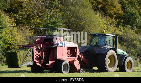 In Sonderborg, Dänemark - Oktober 18, 2018: Traktor mit großpackenpresse sammelt frisches Gras. Stockfoto