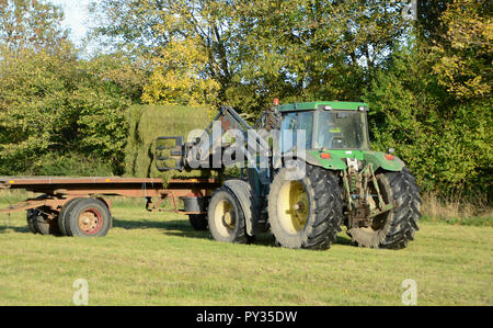 In Sonderborg, Dänemark - Oktober 18, 2018: Traktor lasten Ballen von Gras auf einem Anhänger. Stockfoto