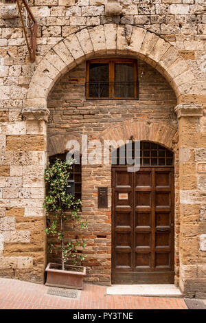 Alte kunstvolle Holz- dooor der antiken Gebäude aus Stein, hoch liegende Stadt San Gimignano, Toskana, Italien Stockfoto