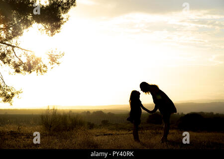 Gegenlicht einer Mutter und Tochter in einem Kiefernwald Mit gelbem Himmel Stockfoto