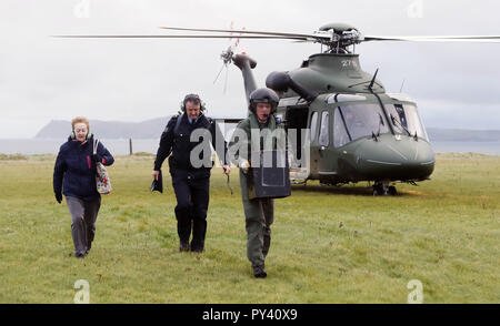 (Von links nach rechts) Vorsitzende Carmel McBride, Gardasee Sgt John Gallagher und Irische Luft Corp Hubschrauber crewman Craig Cullen eine Wahlurne zu Inishbofin Island aus der Grafschaft Galway Zur Präsidentschaftswahl und zum Referendum in Irland über Blasphemie liefern. Stockfoto