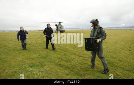 (Von links nach rechts) Vorsitzende Carmel McBride, Gardasee Sgt John Gallagher und Irische Luft Corp Hubschrauber crewman Craig Cullen eine Wahlurne zu Inishbofin Island aus der Grafschaft Galway Zur Präsidentschaftswahl und zum Referendum in Irland über Blasphemie liefern. Stockfoto