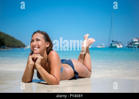 Schöne junge Frau am Strand liegen und lächelnd Stockfoto