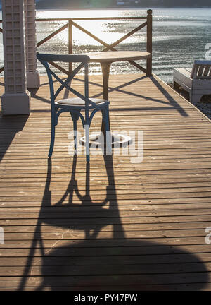 Cafe im Freien mit Tisch und Stuhl am Meer am Morgen bei Sonnenaufgang Stockfoto