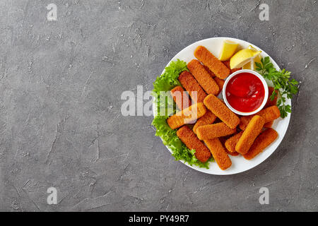 Ansicht von oben Der panierte Fischstäbchen serviert auf einem weißen Teller mit Zitrone, Salatblätter und Tomaten Sauce, Ansicht von oben, flach Stockfoto