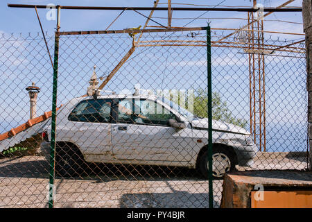 Alte kaputte Auto hinter dem Zaun gegen den blauen Himmel Stockfoto